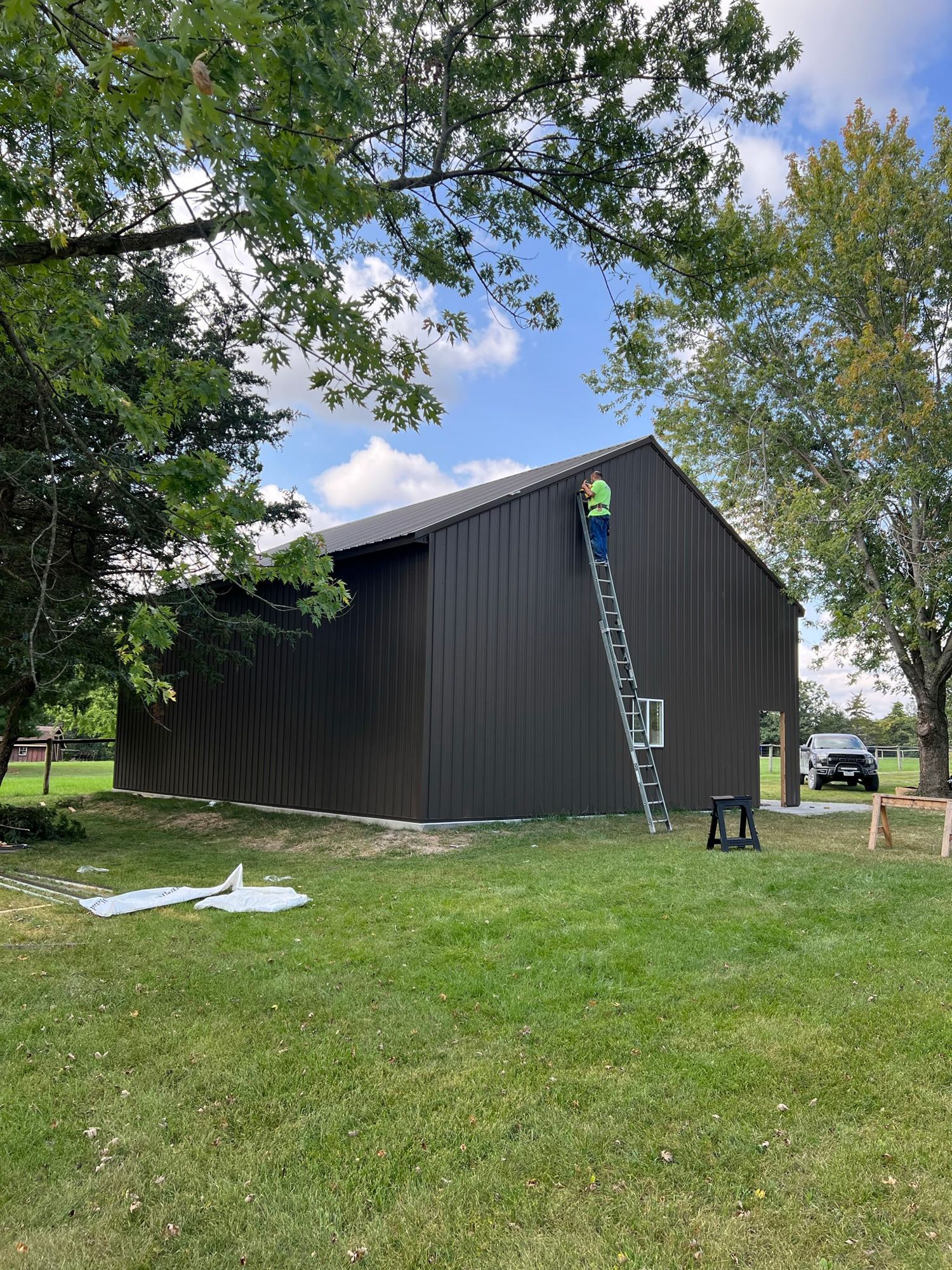 A man is standing on a ladder painting a newly built home.
