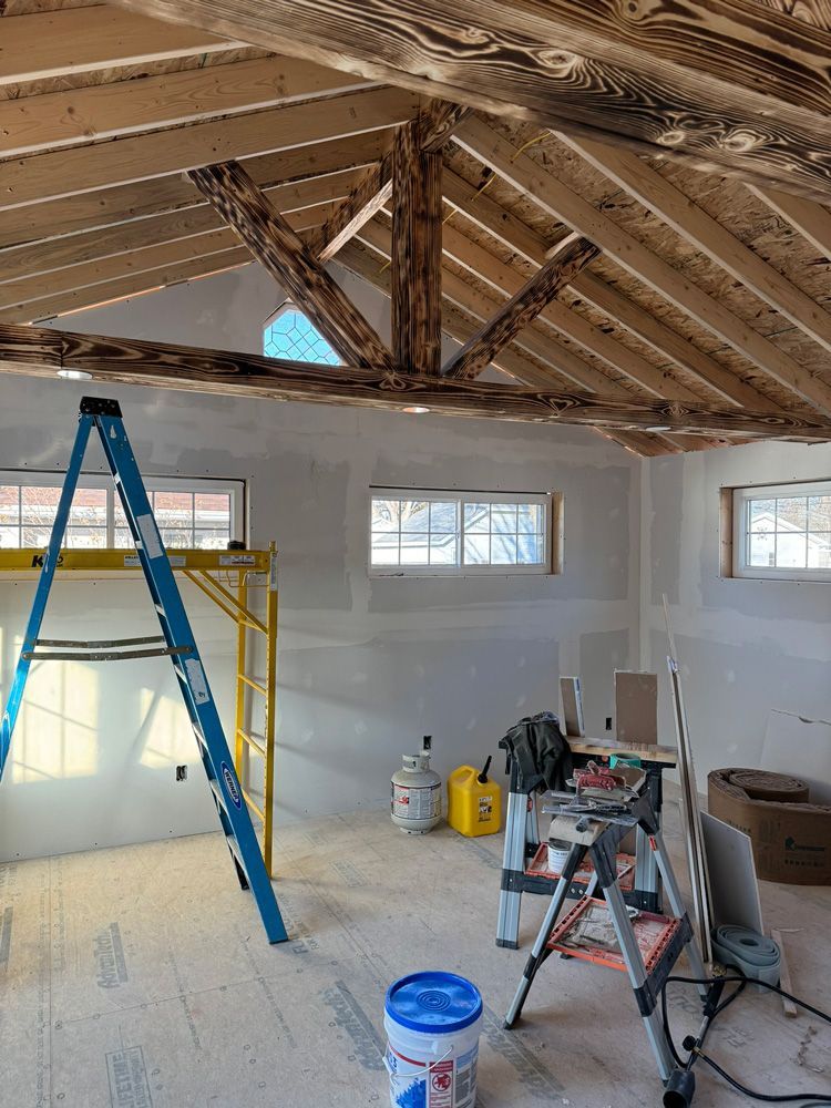 A room under construction with a ladder and a bucket of paint.