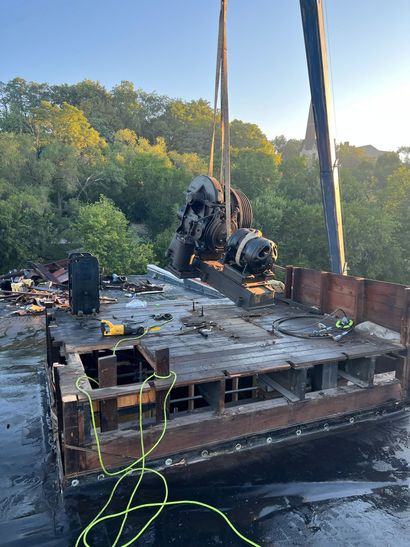A large piece of metal is being lifted by a crane.