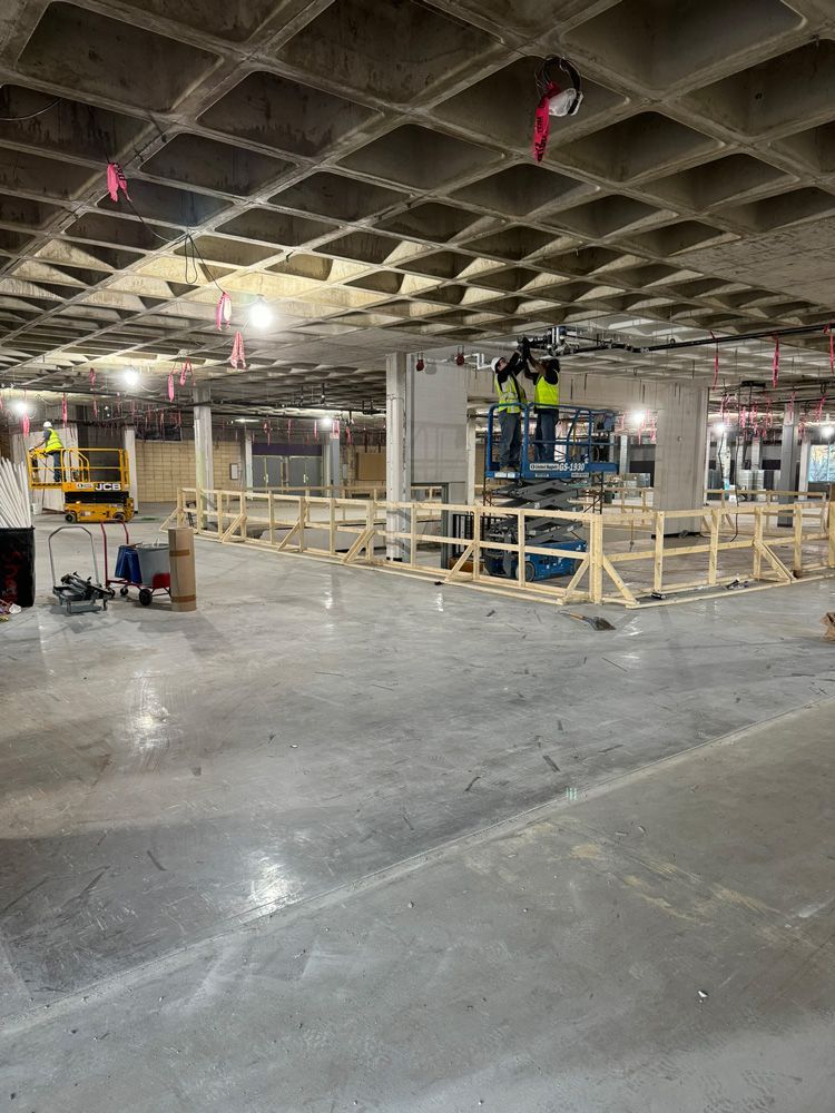 A construction site with a concrete ceiling and a wooden fence in a basement.