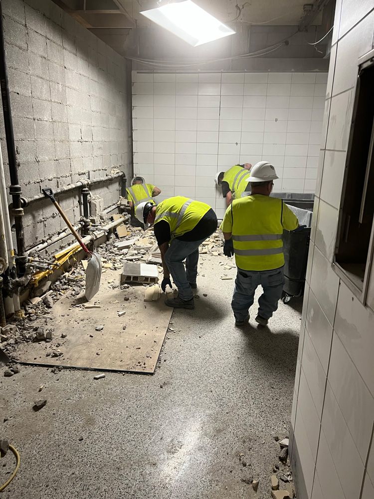 A group of construction workers are working on the floor of a building basement.