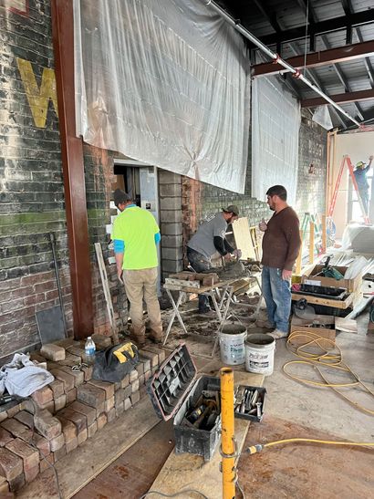 A group of men are working on a brick wall in a building.