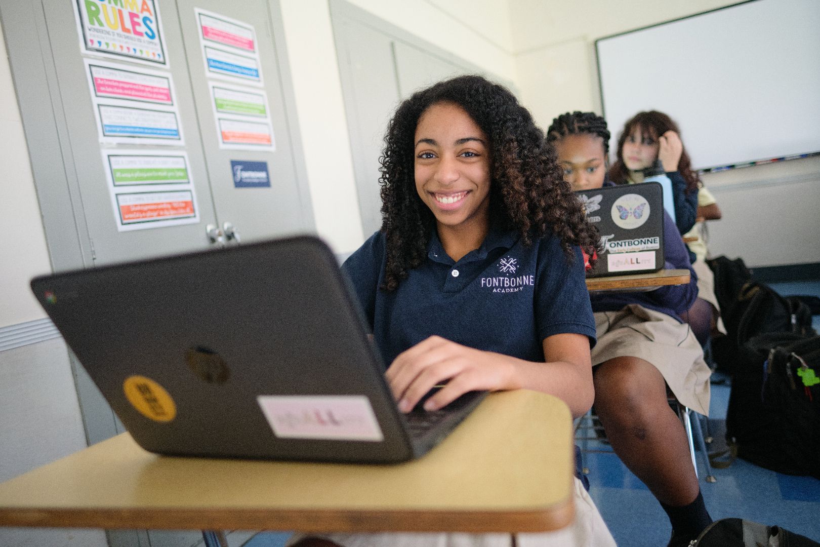 a girl sits at a desk with an apple laptop