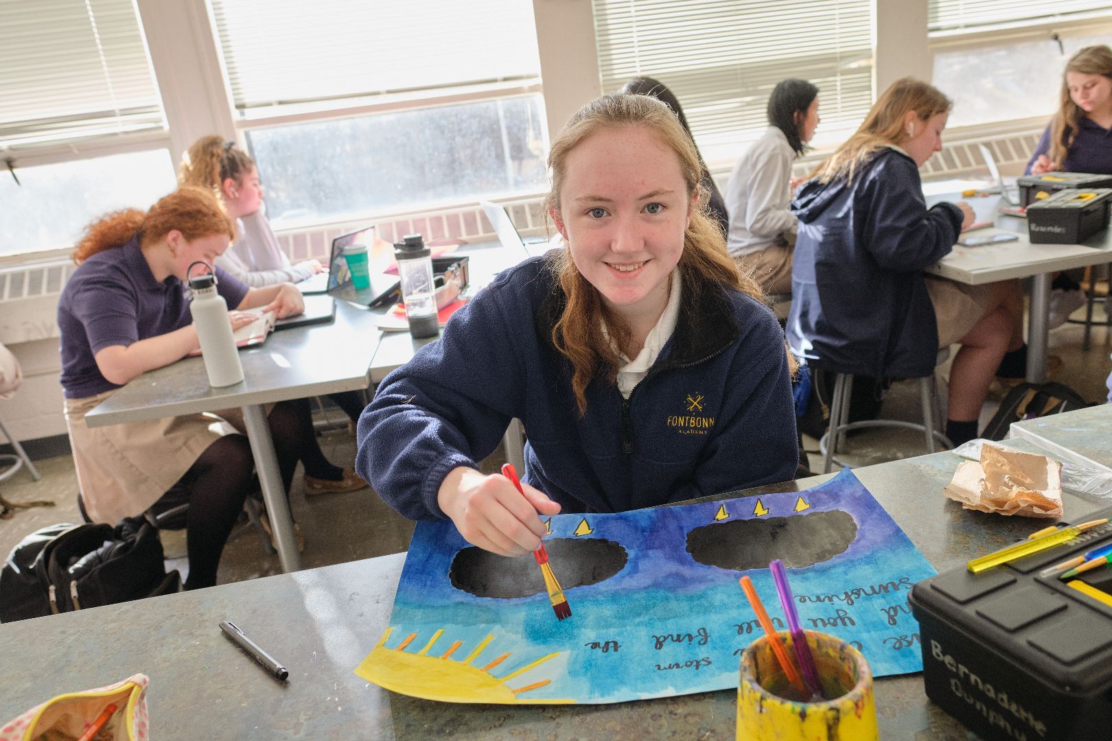 a girl is sitting at a table painting a picture