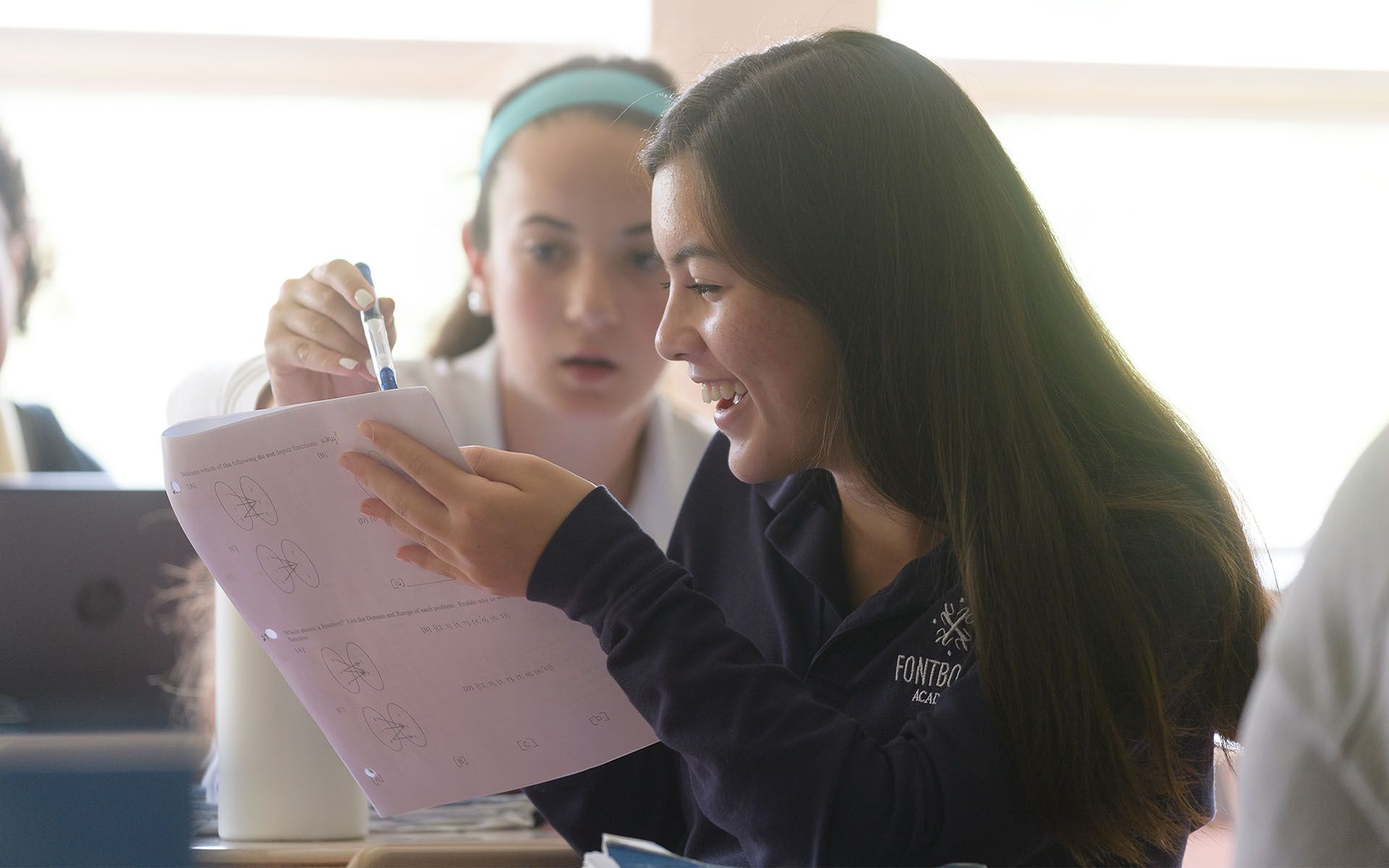 two girls are sitting at a table looking at a piece of paper