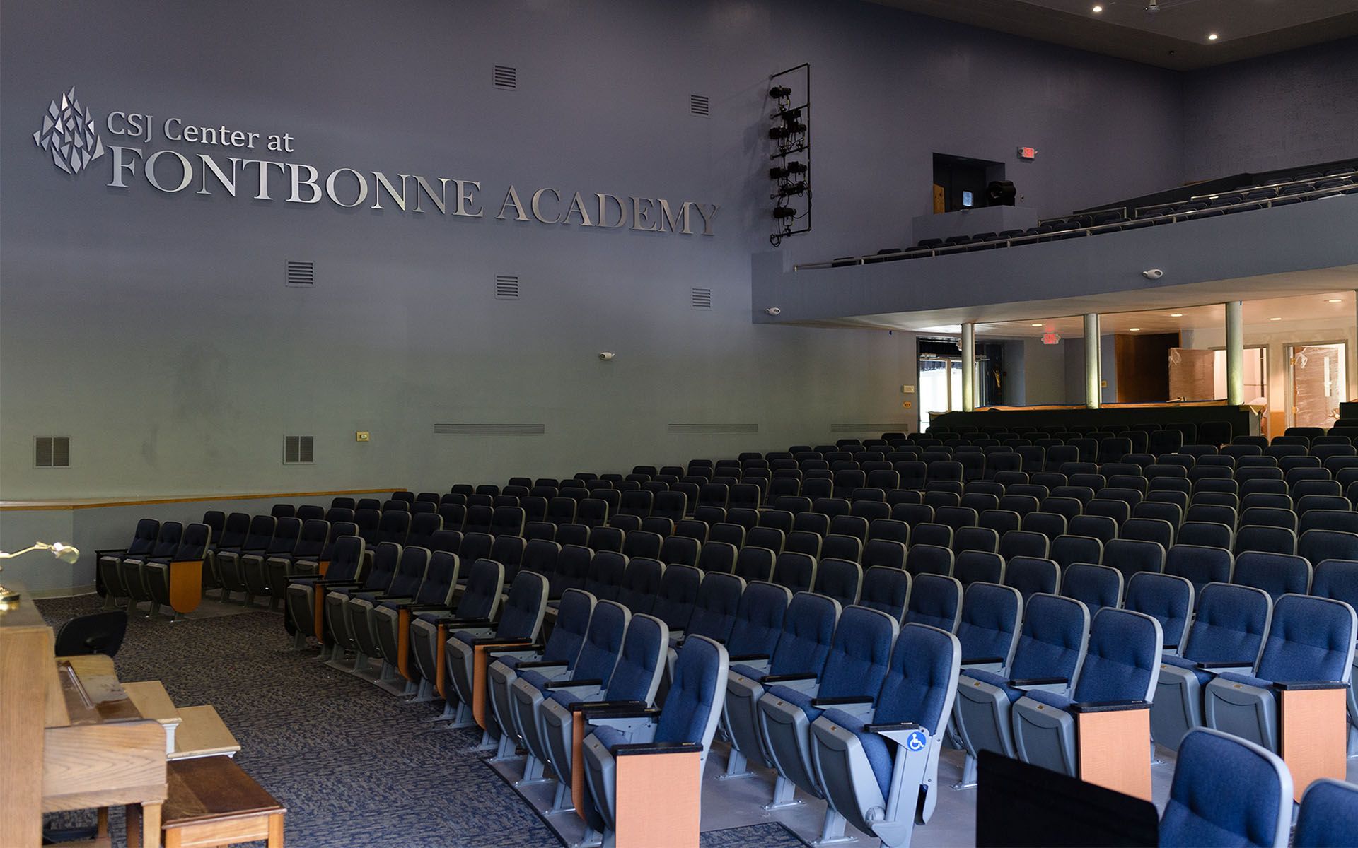 a large auditorium with rows of blue seats and a sign on the wall that says