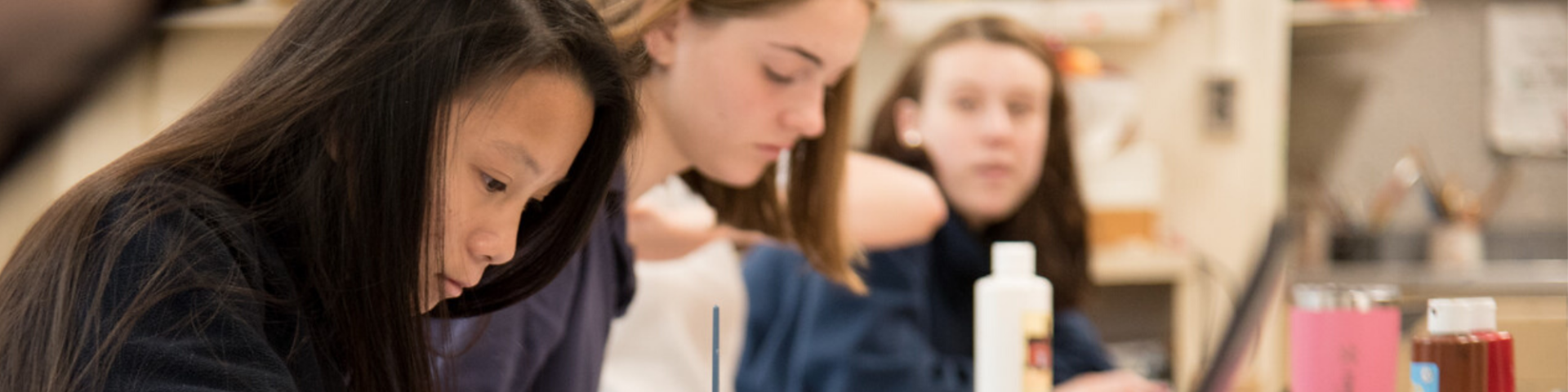 a group of young girls are sitting at a table in a classroom .