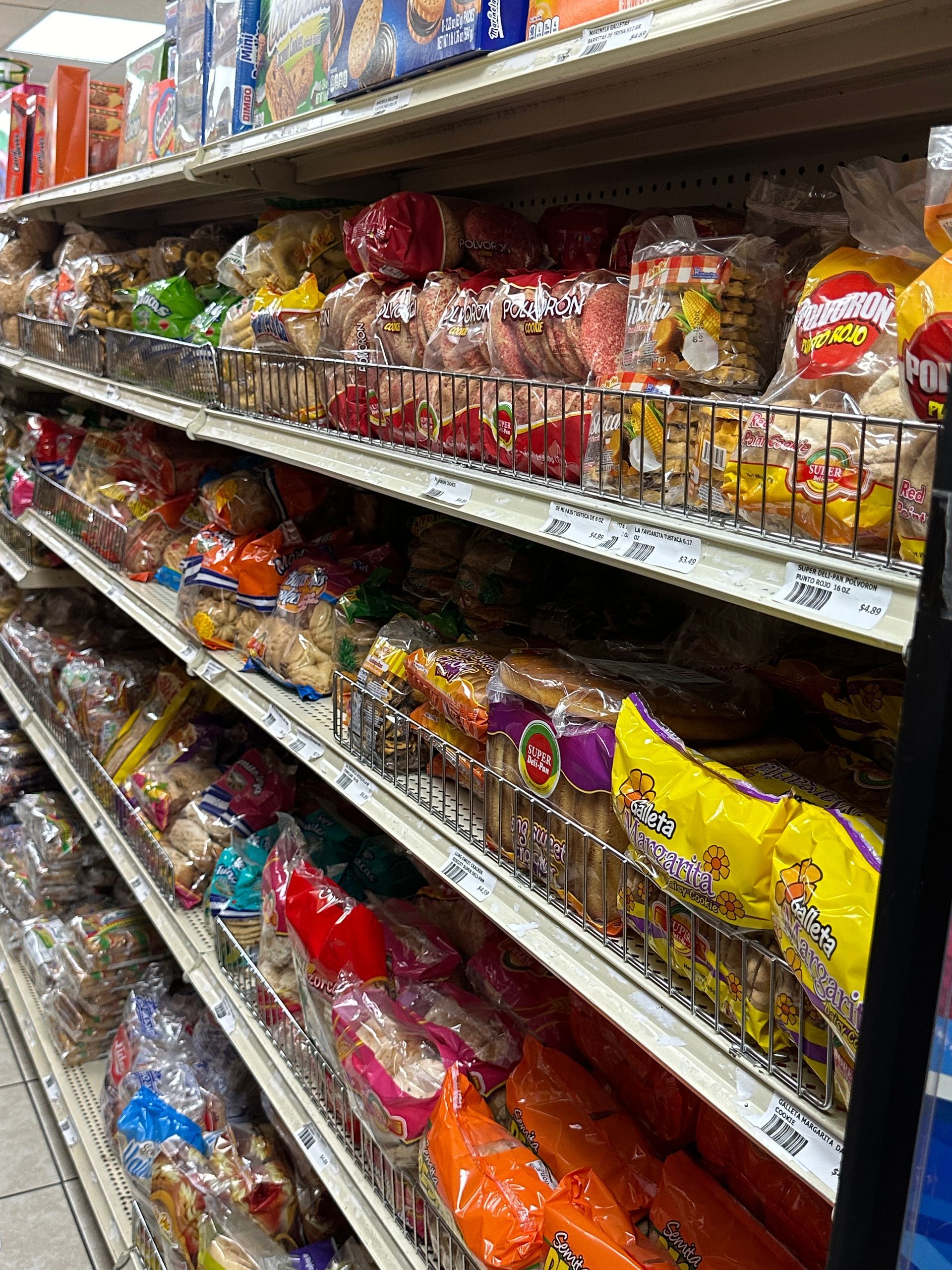 Shelves stocked with various bread loaves in a grocery store.