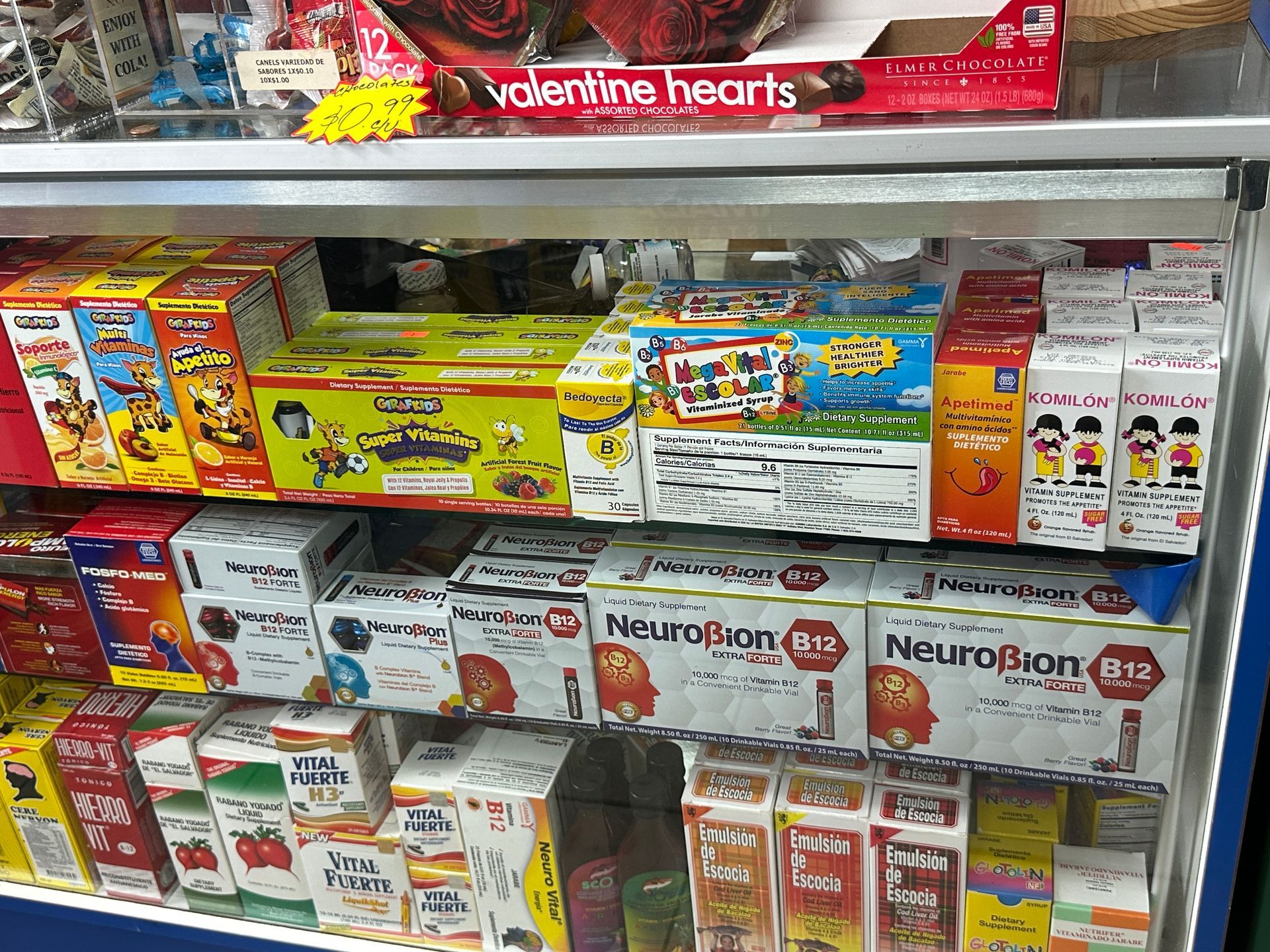 Shelves in a store filled with various boxes of medicine and Valentine's Day candy.
