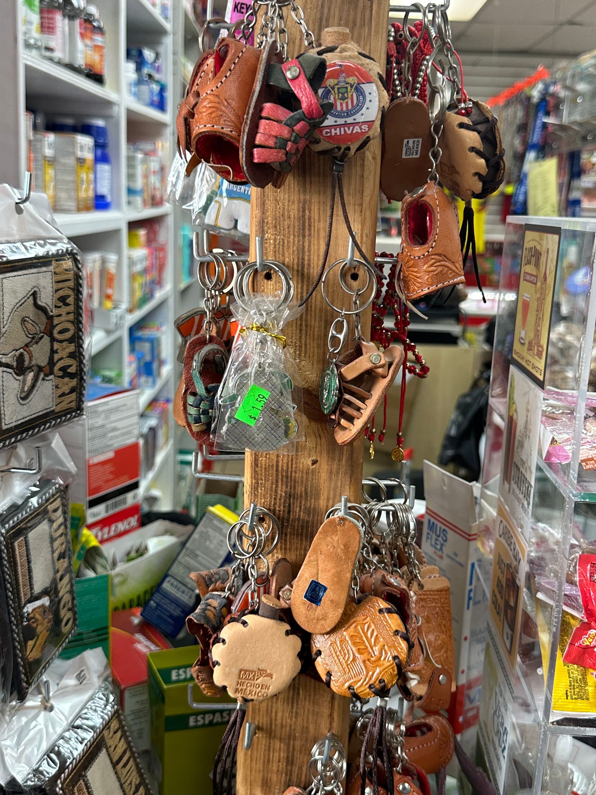 A wooden display stand holding keychains of various shapes, inside a store with shelves of merchandise.