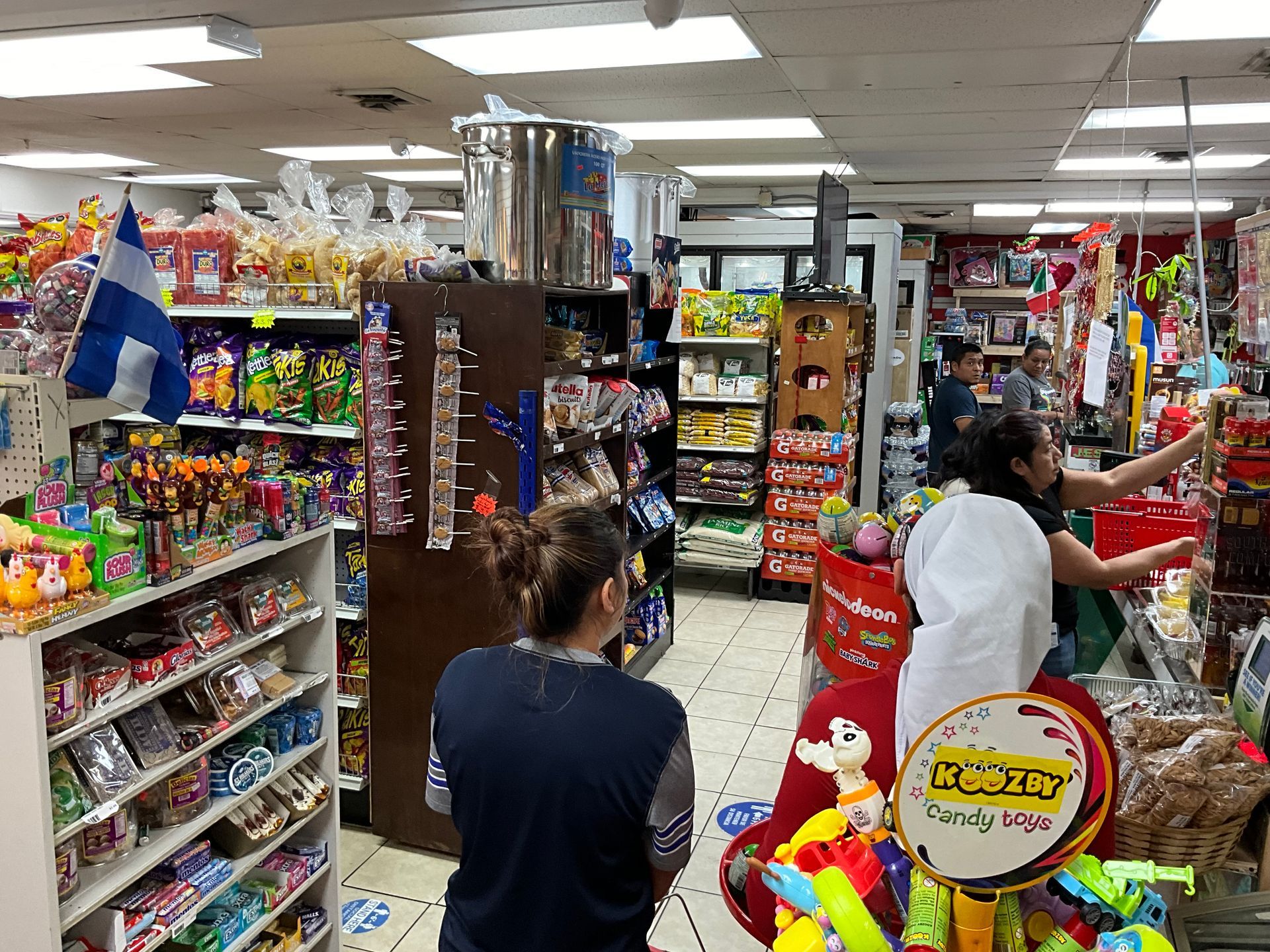 Inside a convenience store with shelves of snacks and products; customers shop.