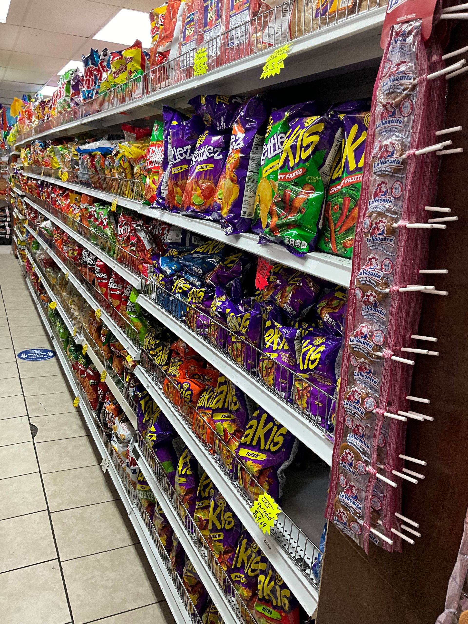 Shelves stocked with various colorful bags of chips and snacks in a store aisle.