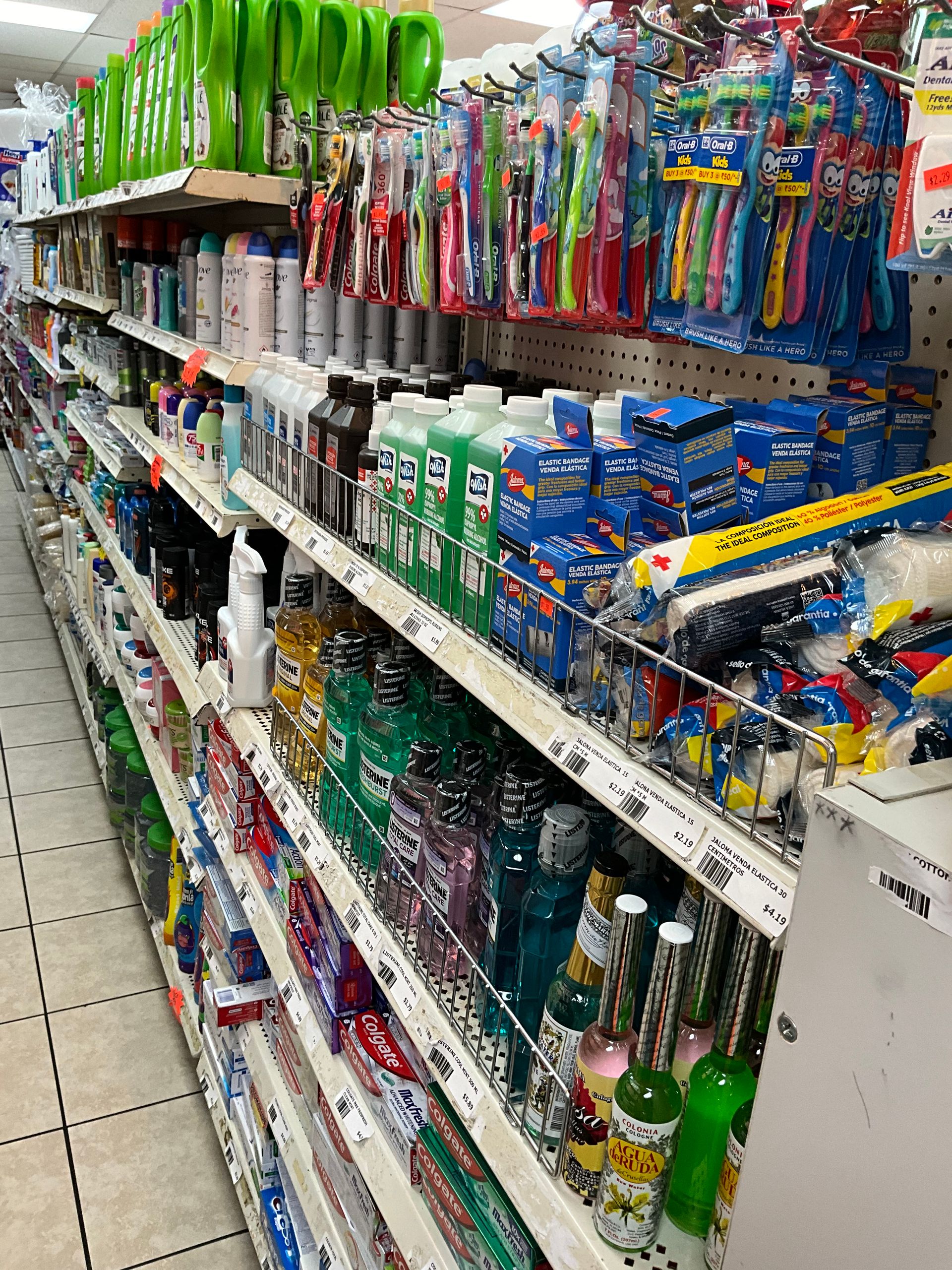 Shelves stocked with personal care products, including toothbrushes, shampoo, and mouthwash, in a store.