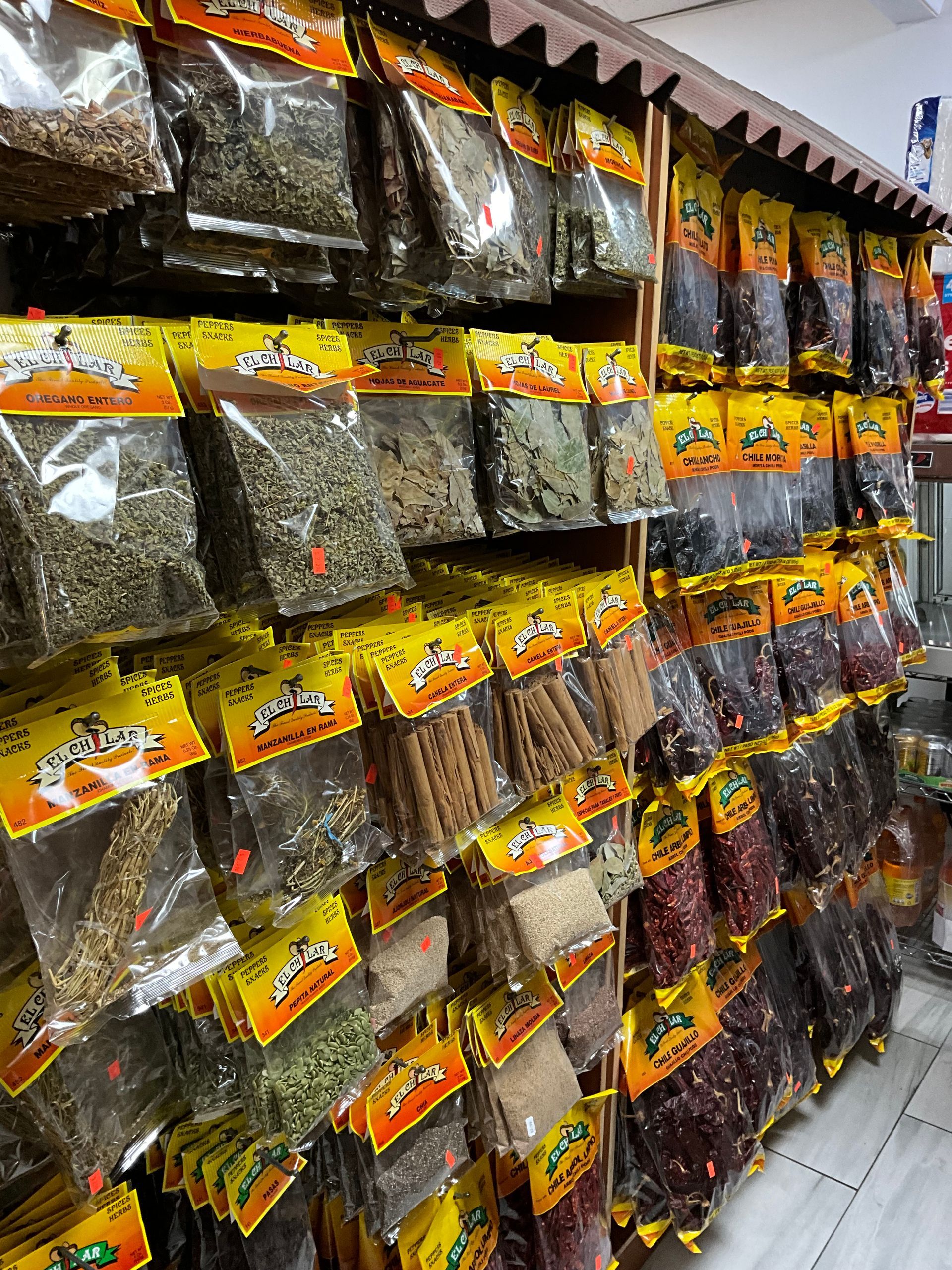 Shelves of various spices in clear bags with yellow labels.