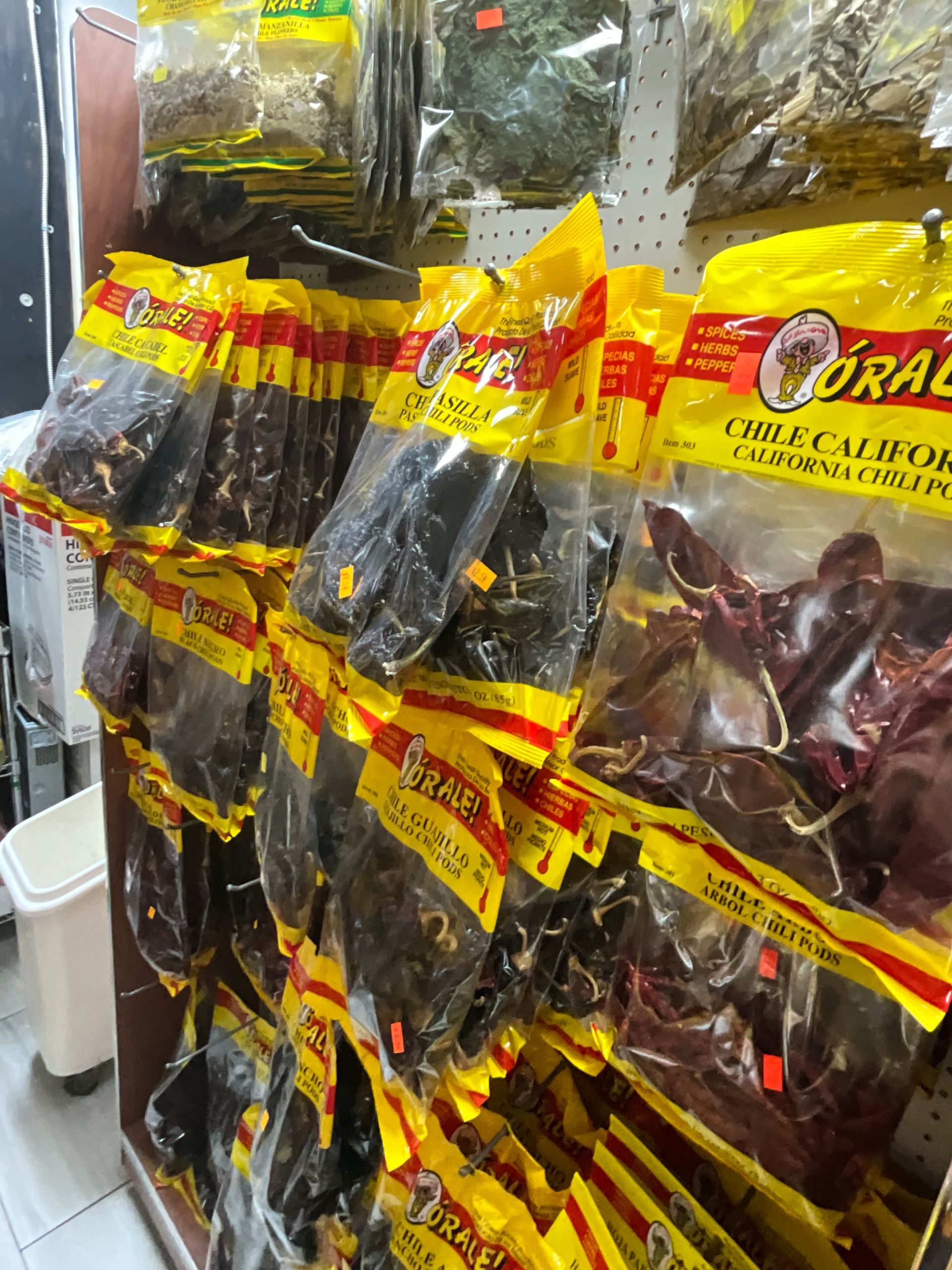 Bags of dried beef products with yellow and red labels hanging on a store shelf.