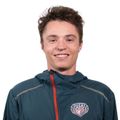 A young man wearing a  jacket smiles for the camera
