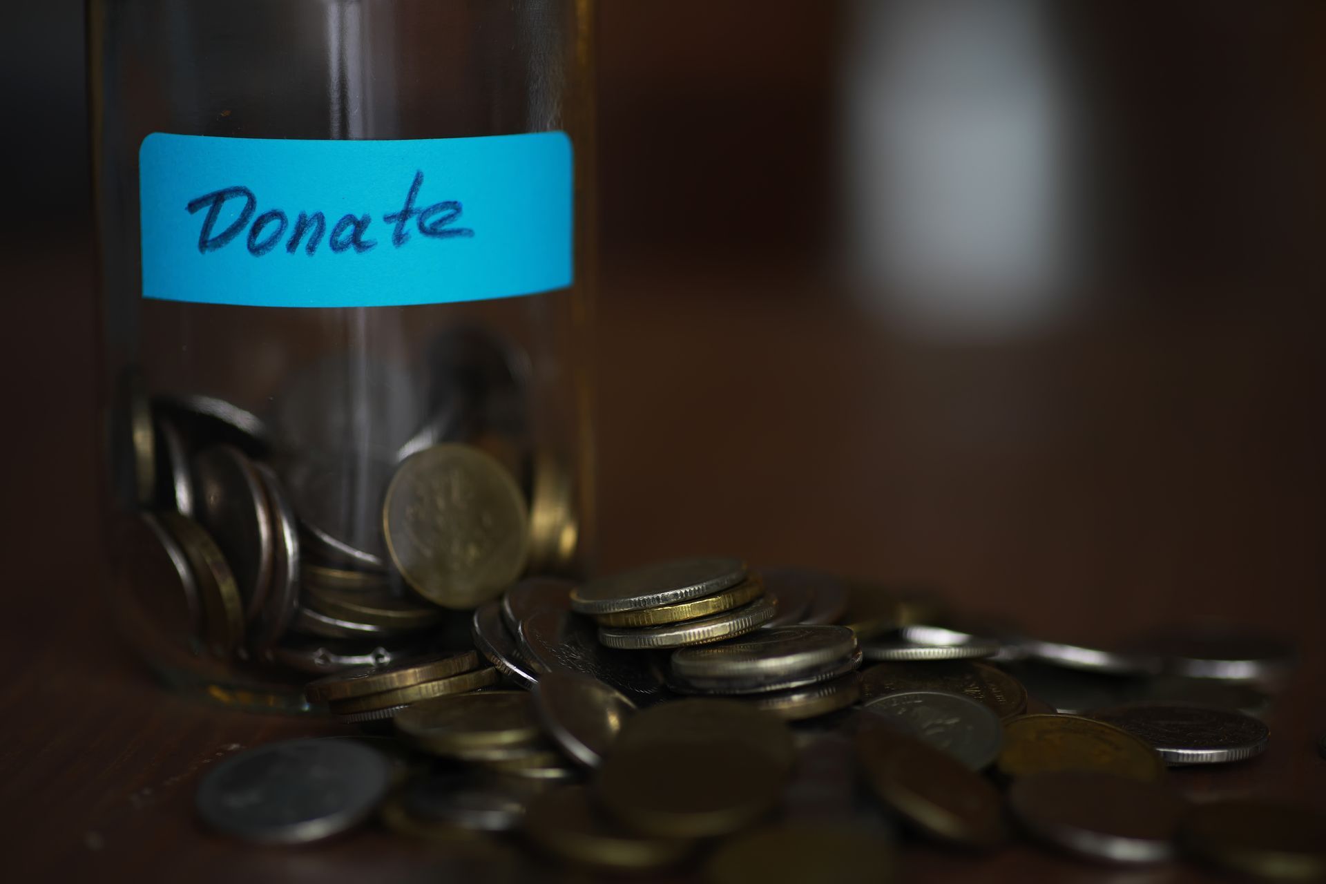 A glass jar filled with coins and a blue label that says