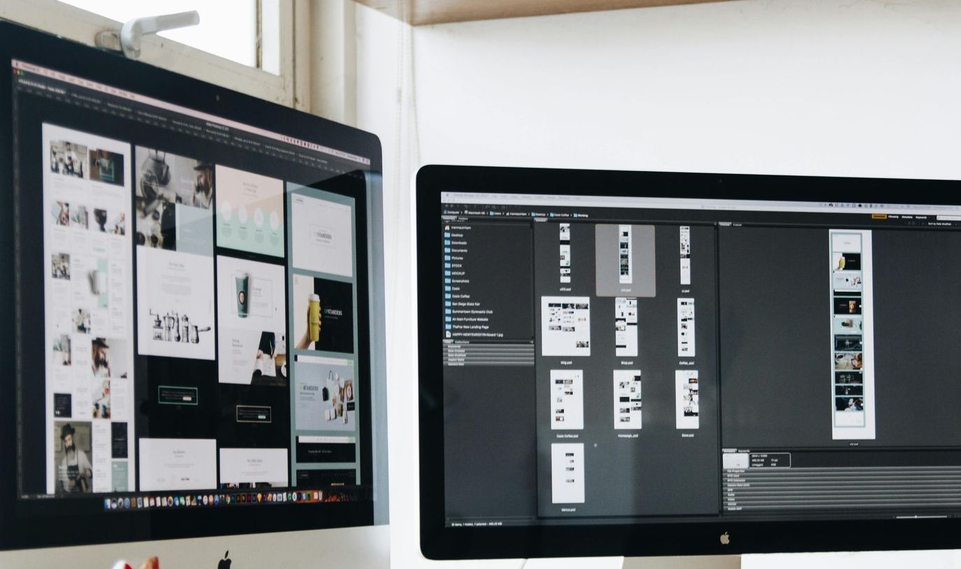 Two computer monitors are sitting next to each other on a desk.