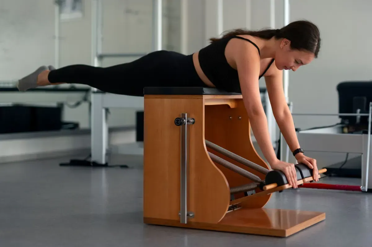 Two people exercising on reformer machines in a long studio hallway