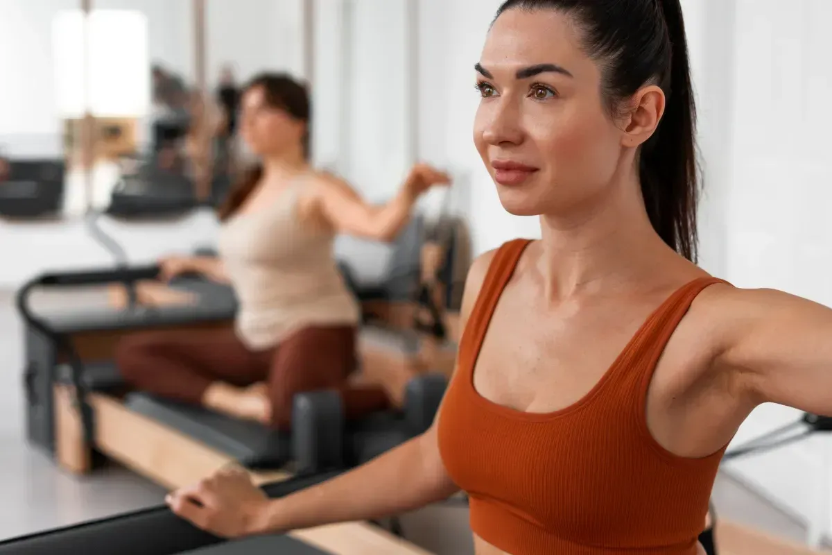 Two people exercising on reformer machines in a long studio hallway
