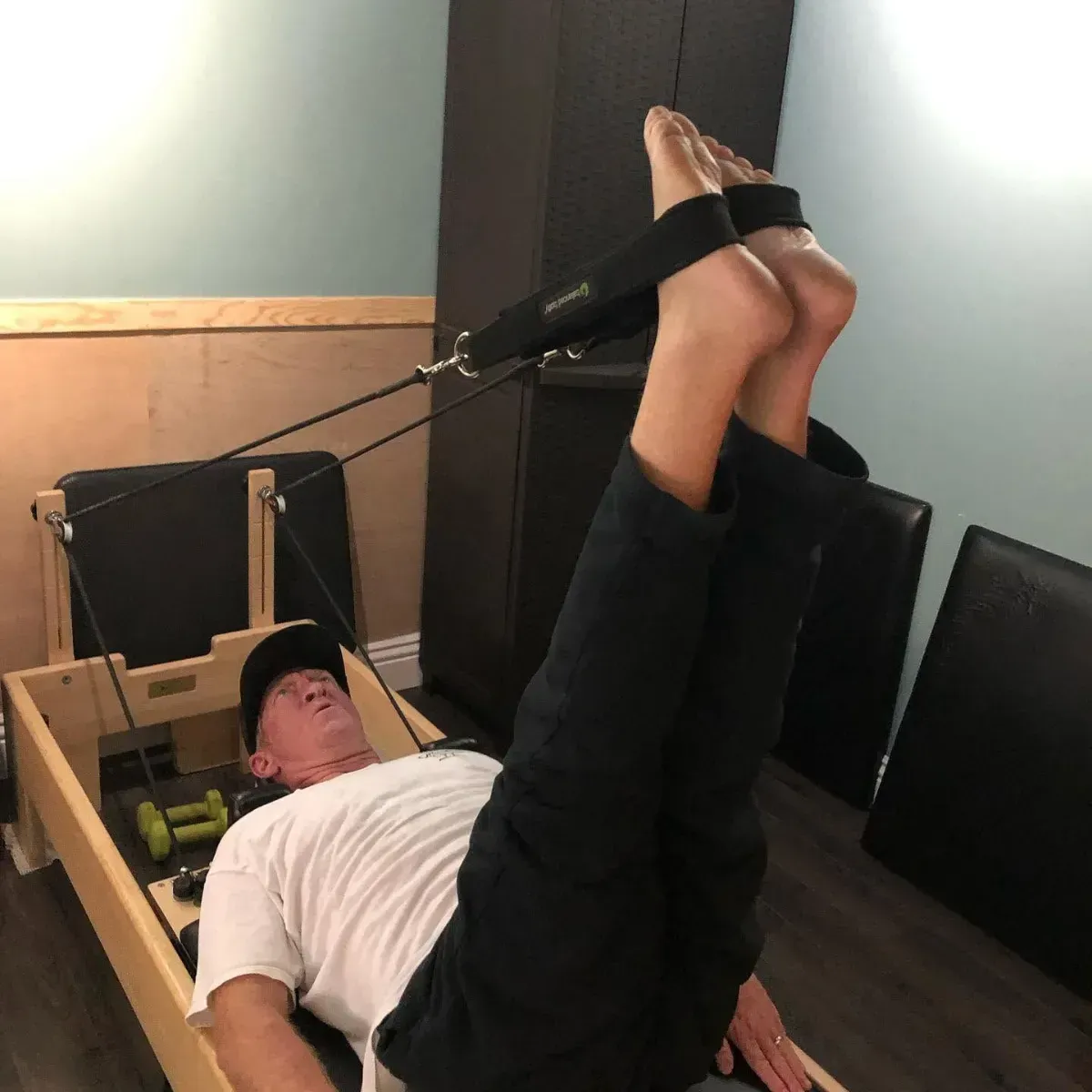 Two people exercising on reformer machines in a long studio hallway