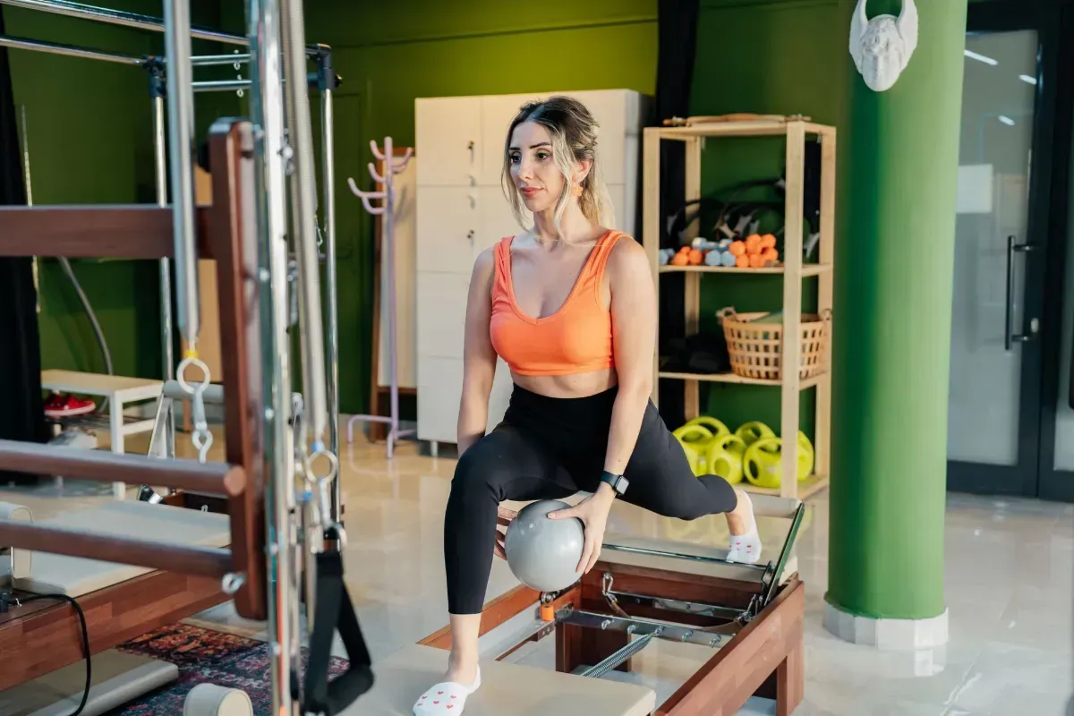 Two people exercising on reformer machines in a long studio hallway
