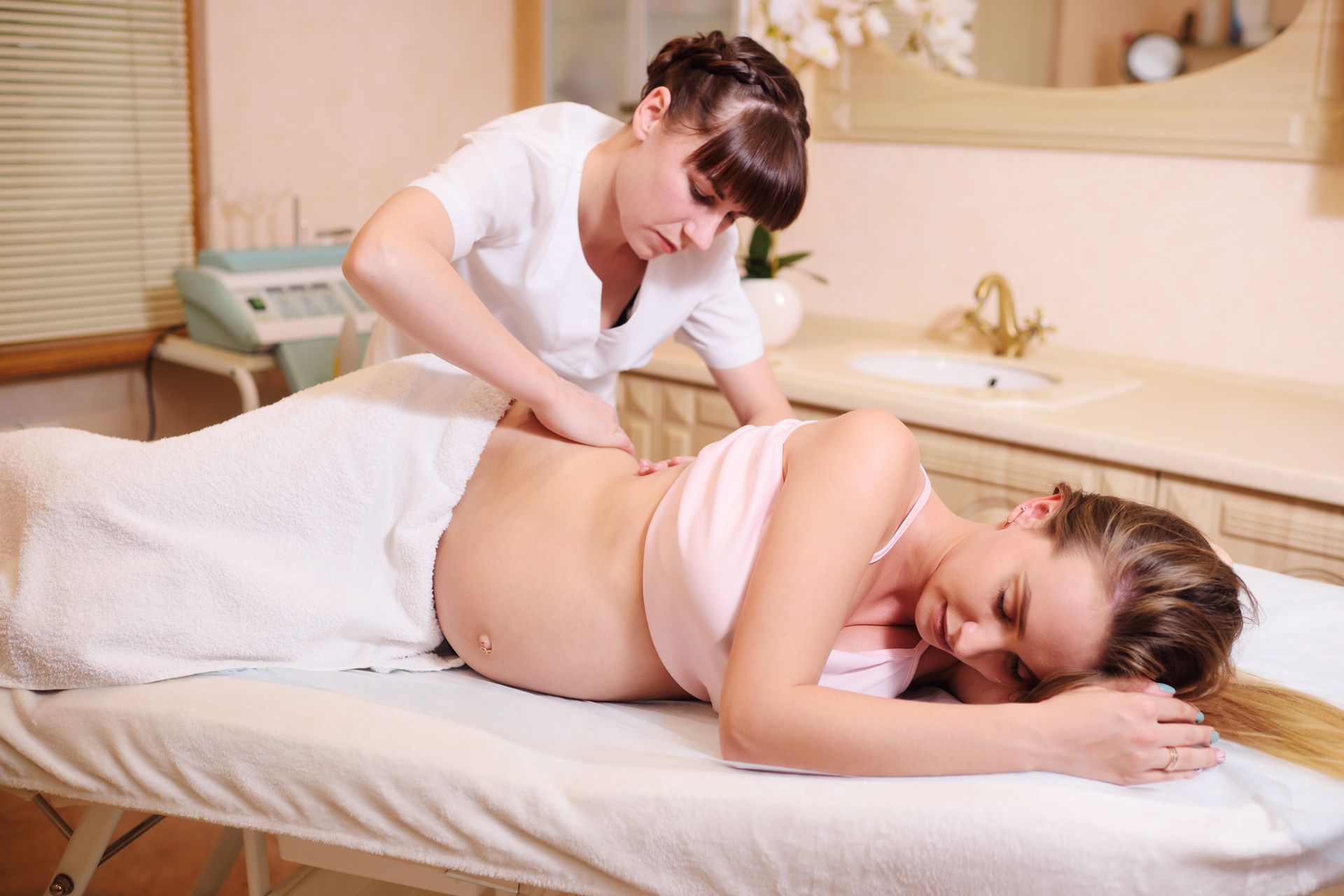A pregnant woman is getting a massage at a spa.