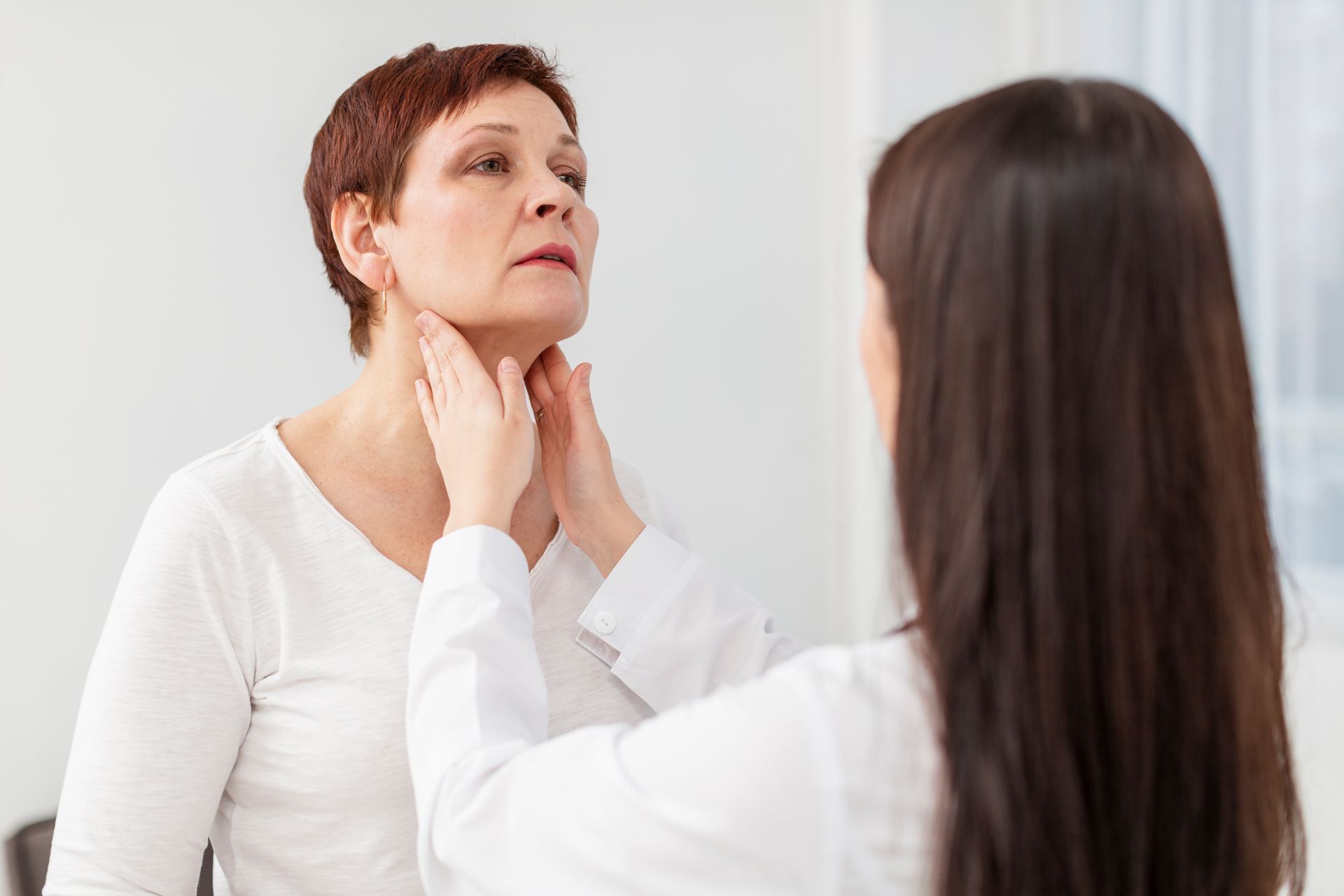 A doctor is examining a woman 's thyroid gland.