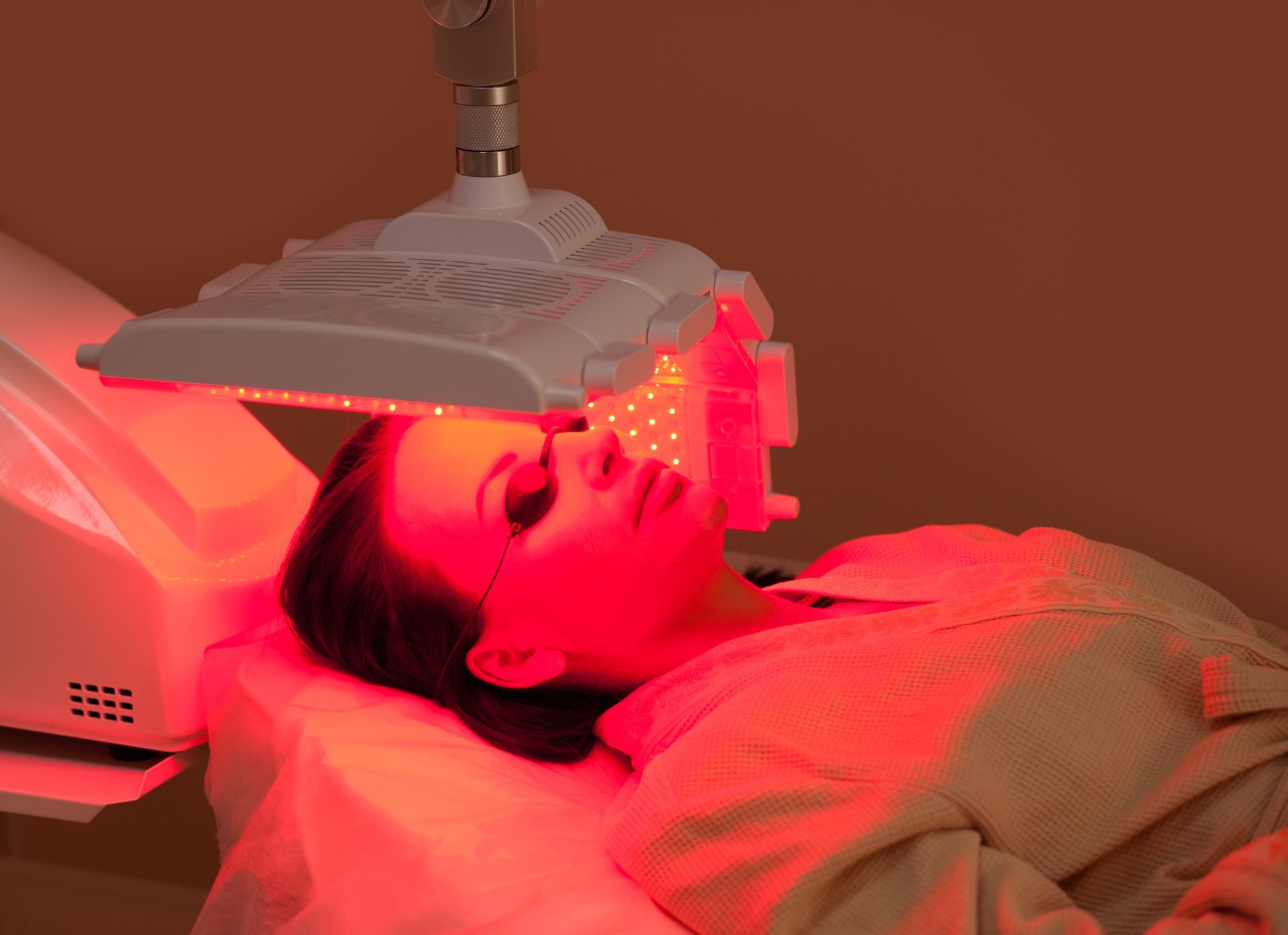 A woman is getting a red light treatment on her face.