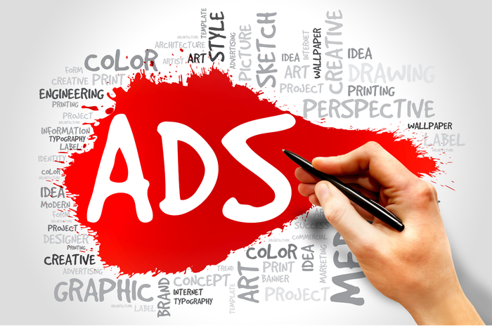 A hand is writing the word ads with a pen