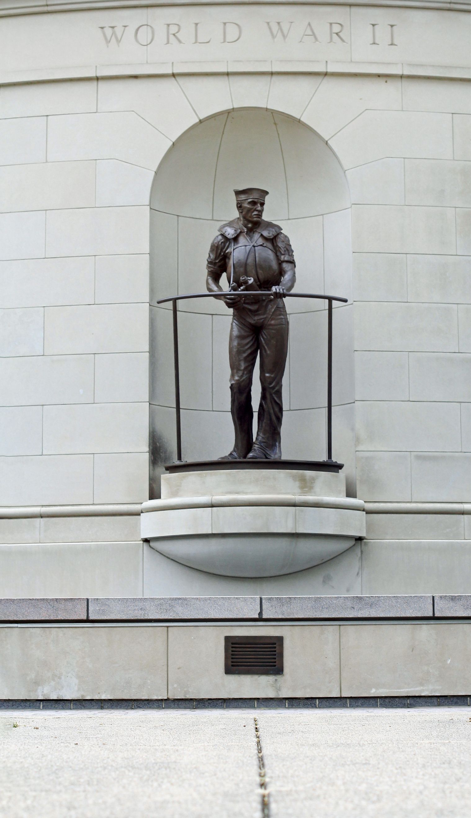 Bronze statue of a soldier in a stone alcove labeled 