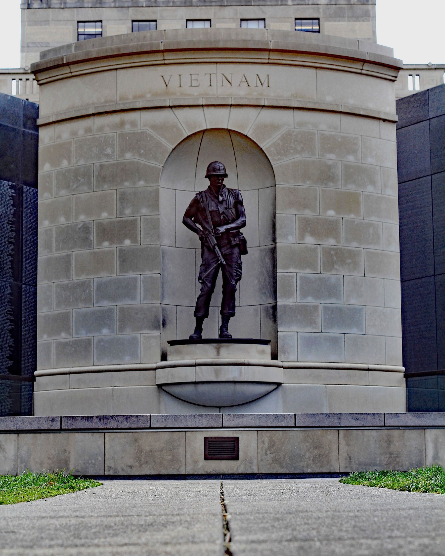 A bronze statue of a soldier in a niche with the word 