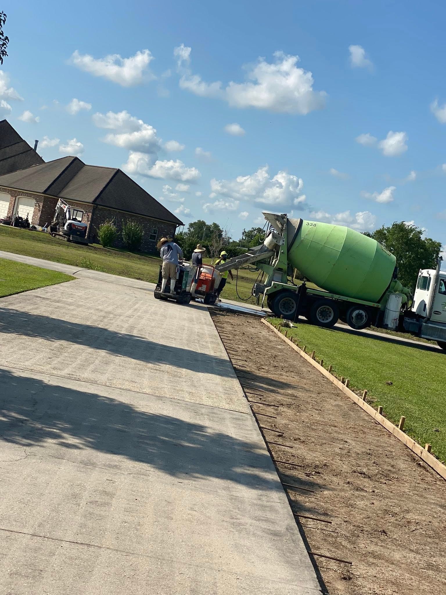 A lime-green concrete mixer truck pours concrete onto a residential construction site on a sunny day.