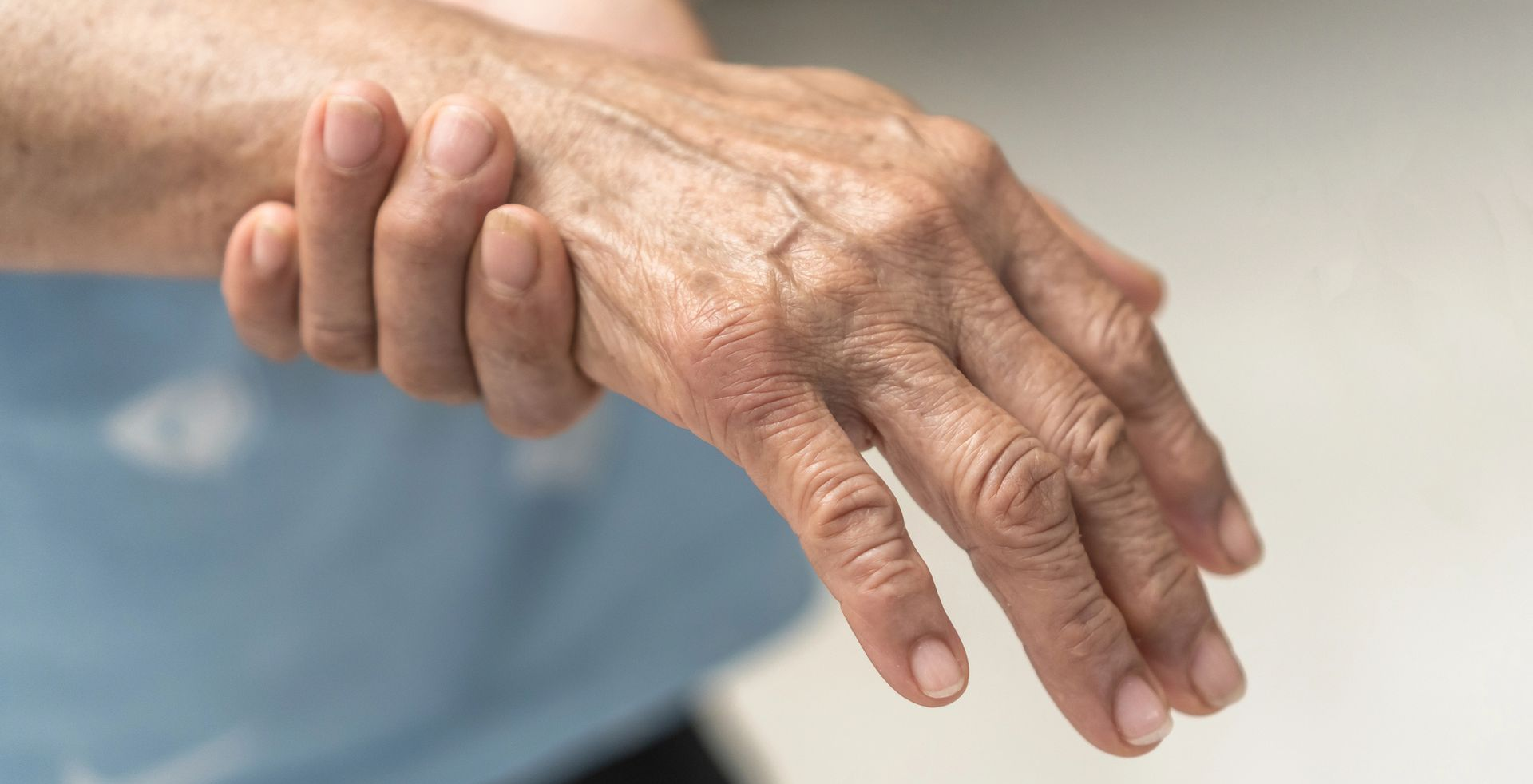Close-up of an elderly hand resting on a person’s forearm against a blurred background