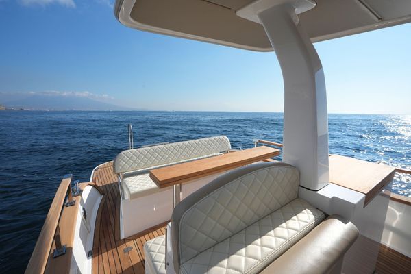 Ponte di yacht di lusso con comode sedute imbottite affacciato su un oceano blu brillante sotto un cielo limpido.