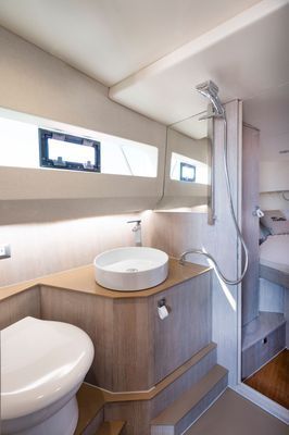 Bagno compatto con WC, lavabo, doccia e mobiletto in legno in un piccolo spazio moderno.