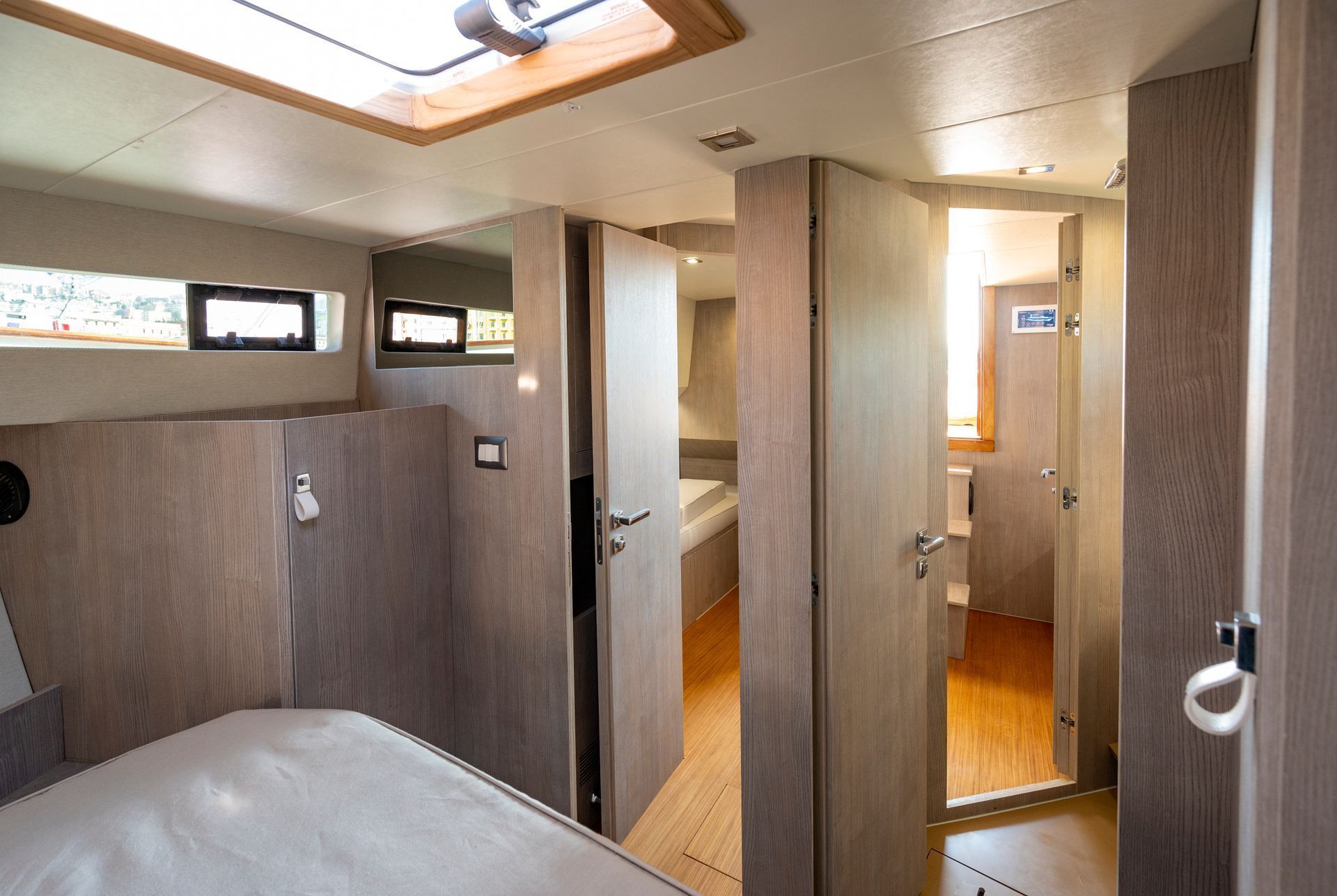 Interno compatto della cabina con pannelli in legno, un letto e un piccolo bagno visibile attraverso le porte aperte.
