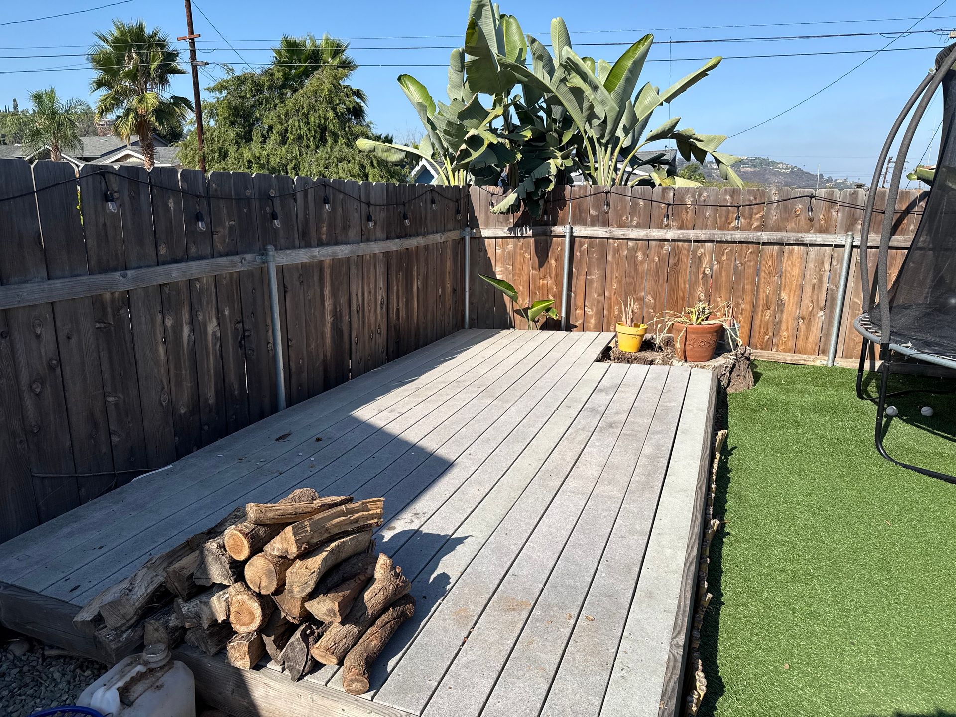 Pile of assorted weathered wooden planks, a ladder, and a frame; outdoor setting.