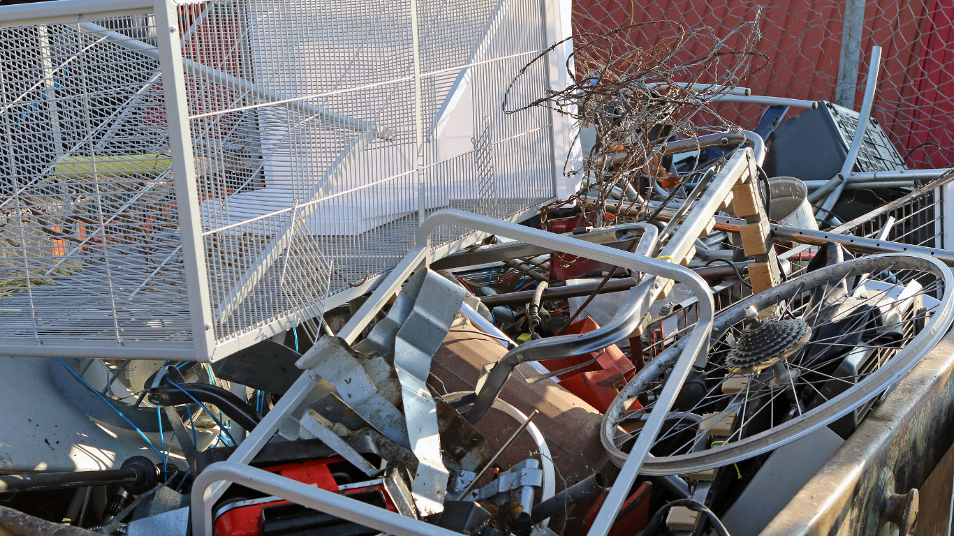 Scrap metal pile with a shopping cart, bicycle parts, and other metal objects.