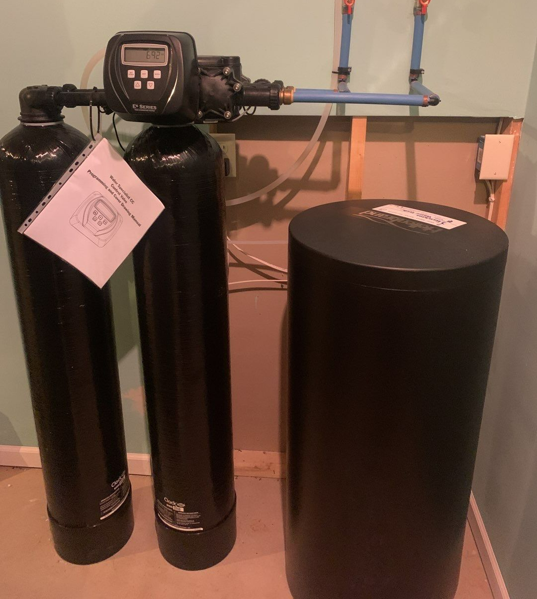 Water softener system with two black tanks and a salt storage tank.