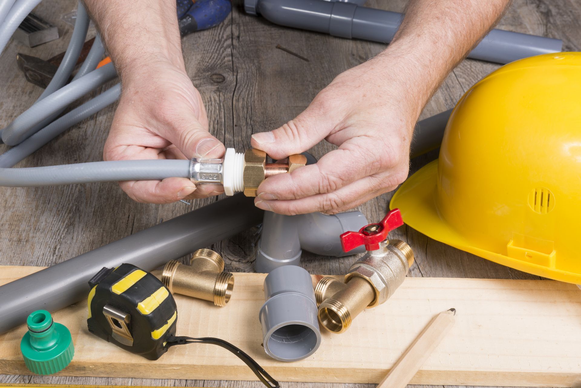 Plumber connecting PEX pipe with brass fittings and valve, 
surrounded by plumbing tools and gear.