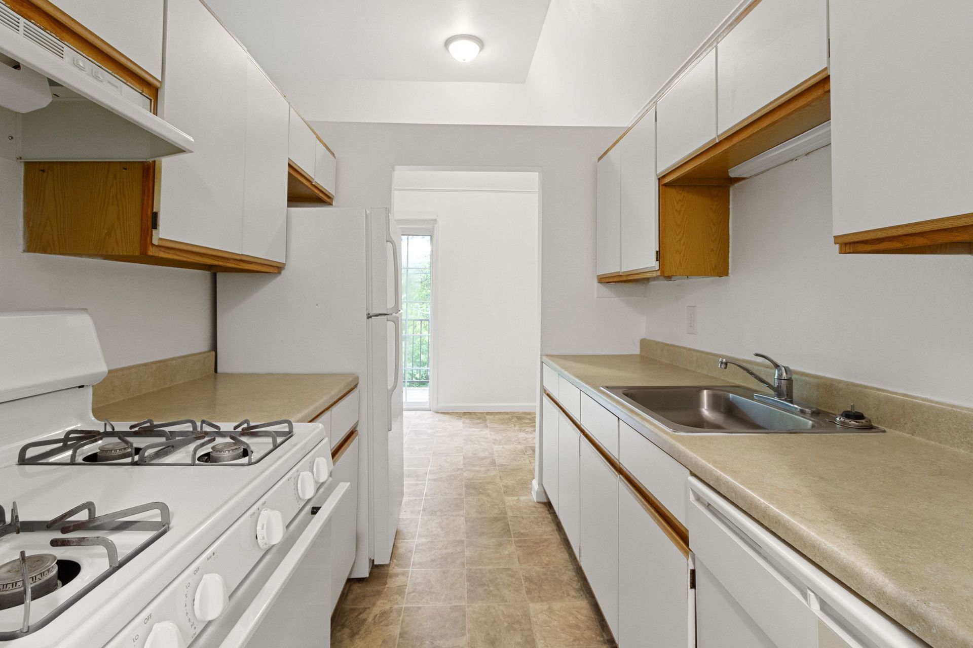 White kitchen with appliances and cabinets; view toward an open doorway.
