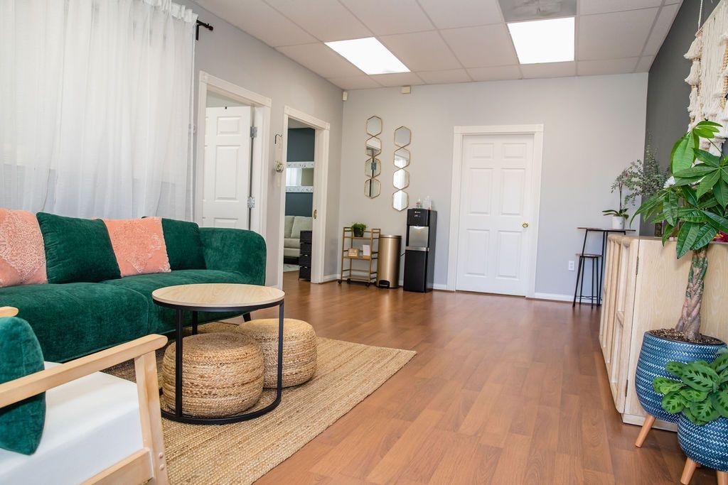 Bright living room with green sofa, woven coffee table, plants, and hardwood floors