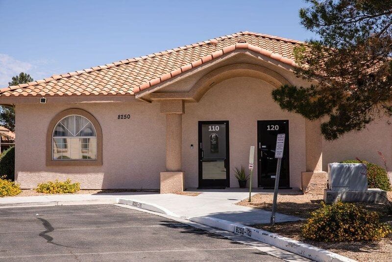 Single-story stucco office building with a tiled roof and two entrance doors by a parking lot