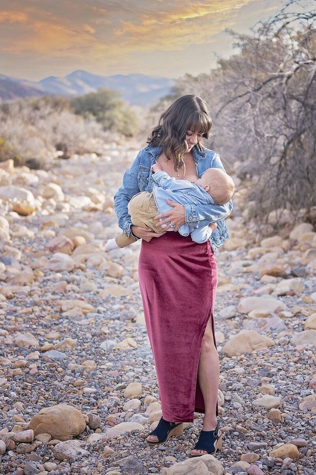 Woman holding a child in a rocky desert landscape at sunset