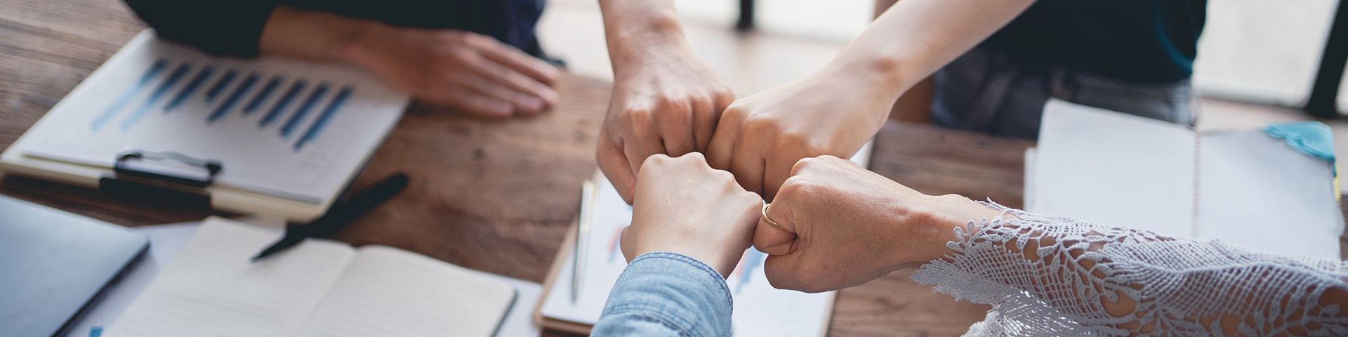 A group of people are putting their hands together in a circle.