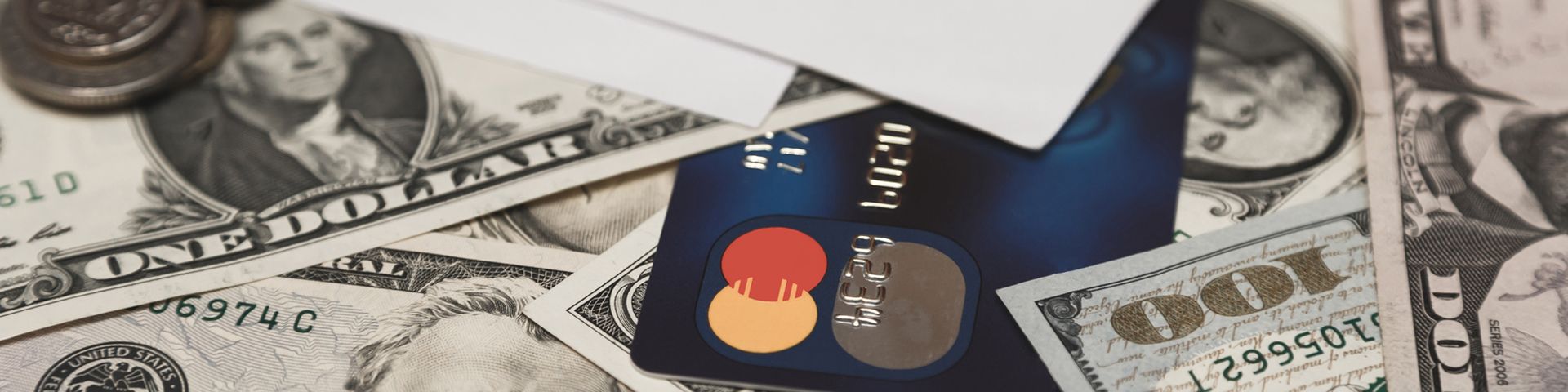 A credit card is laying on top of a pile of money