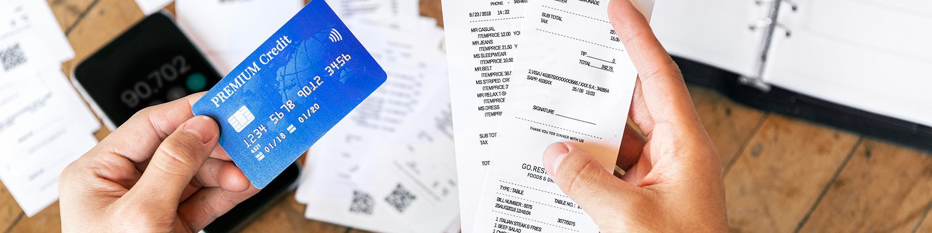 A person is holding a credit card and a receipt.