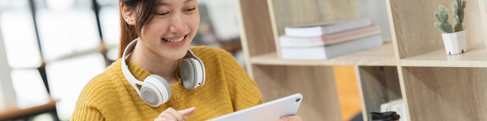 A woman wearing headphones is using a tablet computer.