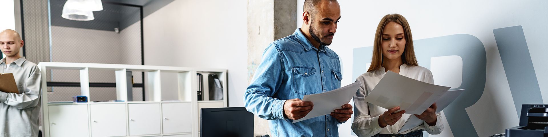 A man and a woman are looking at a piece of paper in an office.